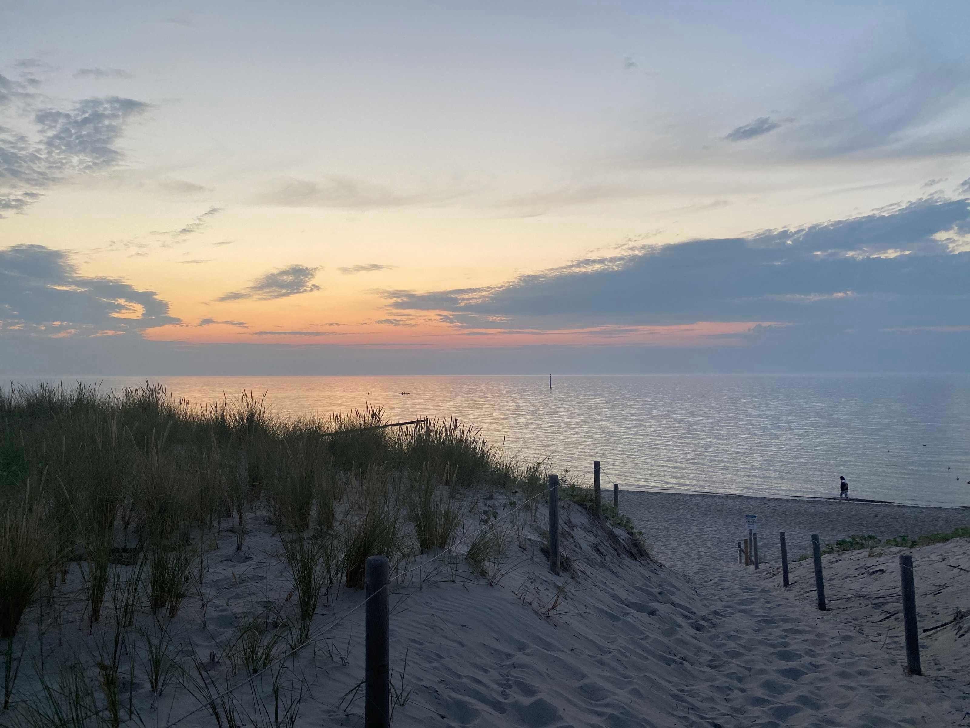 A beach with sand dunes and a fence.