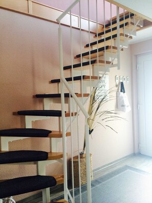 Eine Treppe mit weißen Geländern und Holzstufen, ein gewebter Korb und ein an der Wand befestigtes Schild mit dem Wort 'HOME'.
