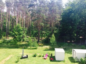 A grassy area with a shed, a small structure, and a tall tree in the background. - *der Strandkater OG / DG Priemer GM 69667 - der Strandkater SNR: 66 (Gelbensande)