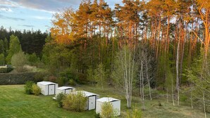En rad vita stugor på en gräsklädd äng med en skog i bakgrunden.