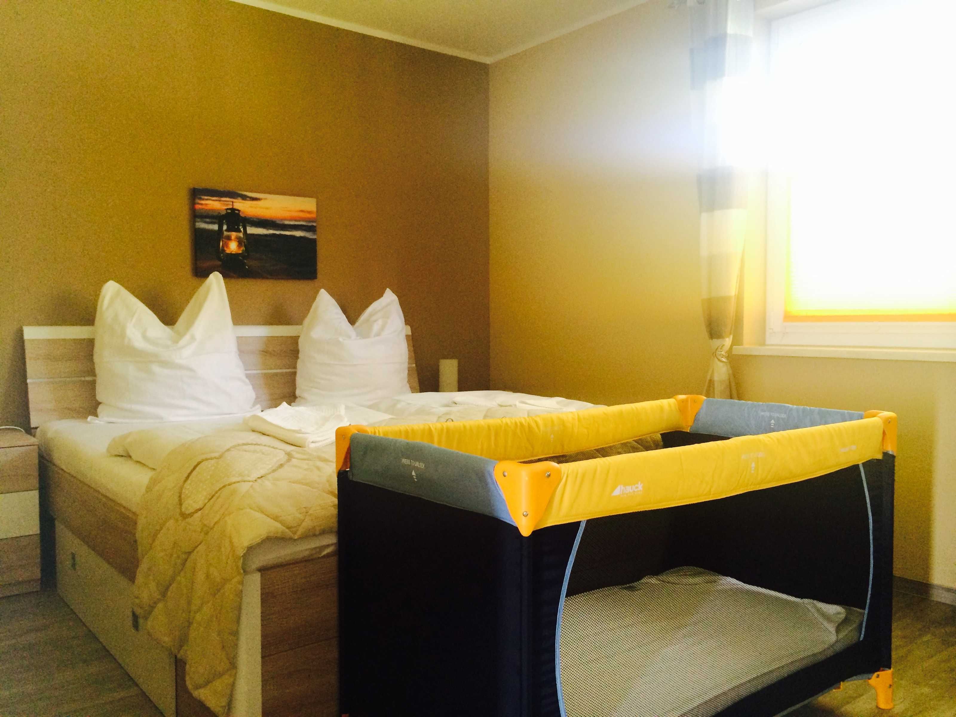 Une chambre d’hôtel avec un lit, des oreillers, un lit superposé, un tableau au mur et une fenêtre.