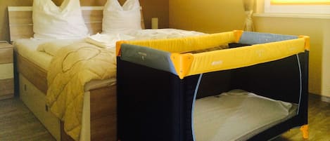 Une chambre d’hôtel avec un lit, des oreillers, un lit superposé, un tableau au mur et une fenêtre.