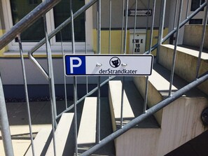 Una escalera metálica con un cartel que indica estacionamiento para 'der Strandkater' con un símbolo de gato.