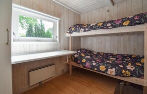Ein Etagenbett mit Blumenmuster-Bettwäsche, ein Fenster mit Blick auf Bäume und ein Holzboden.