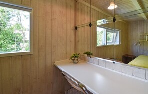 A bathroom with wooden paneling, a white countertop, a mirror, and a window. - 3 bedroom awesome home in Asperup (Asperup)