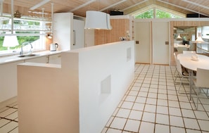 A modern kitchen with white cabinetry, a tiled floor, and a large window providing natural light. - 3 bedroom awesome home in Asperup (Asperup)