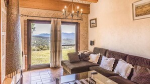 Una sala de estar acogedora con un sofá, una mesa de centro y vistas al campo a través de un ventanal grande.