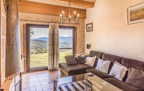 Relax in this inviting living room with a large sofa, glass coffee table, and scenic views through the sliding glass door.