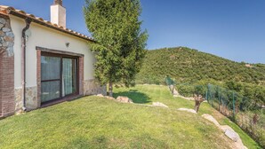 Una casa con fachada de piedra, un ventanal grande y un patio cubierto de césped.
