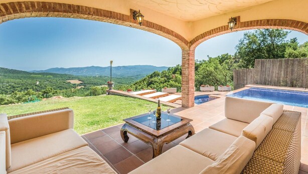 Un espacio al aire libre techado con piscina, sillas de descanso y vistas a las montañas.