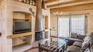 Una sala de estar con chimenea, televisor y sofá.