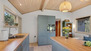A modern kitchen with wooden countertops, a built-in oven, and a hanging light fixture. - 3 bedroom amazing home in Blåvand (Blåvand)