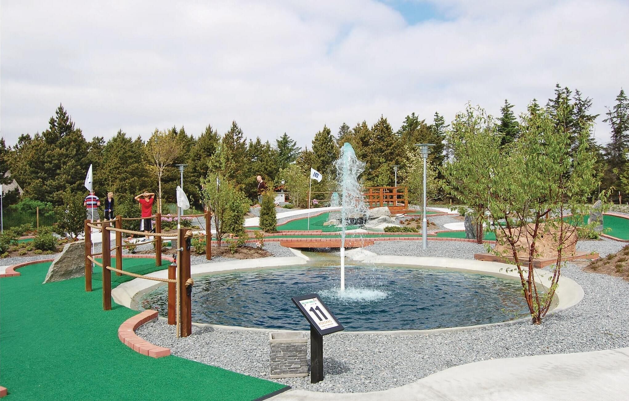 A water park with a central fountain, play structures, and a signpost.