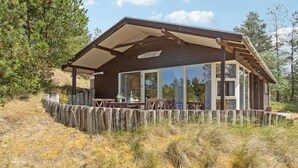 A wooden cabin with a covered patio, large windows, and a sign reading "CAAPAJA". - 3 bedroom amazing home in Blåvand (Blåvand)