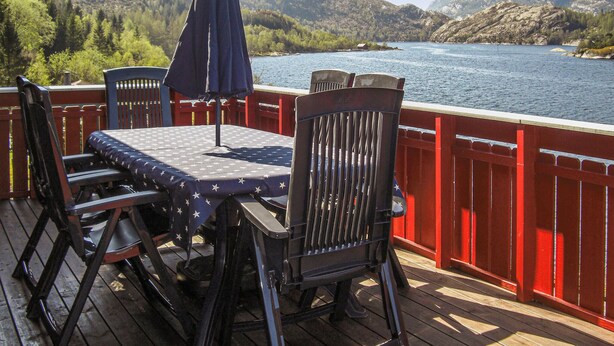 Terraza con mesa y sillas, con vistas a un lago y montañas.