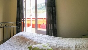 Una cama con un edredón blanco texturizado y un cojín verde con estampado floral.