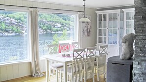 Un comedor con mesa y sillas, vista a un lago, chimenea y un aparador con puertas de vidrio.