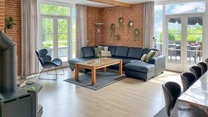 A modern living room with a brick wall, a sofa, a coffee table, and a dining area with chairs.