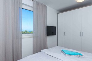 A bedroom with a bed, a TV mounted on the wall, and a wardrobe.