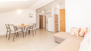 Un appartement moderne comprenant un coin repas, une kitchenette et un salon avec un canapé et des coussins décoratifs.