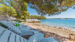 Une zone de plage aménagée avec des chaises longues et un rivage rocheux.