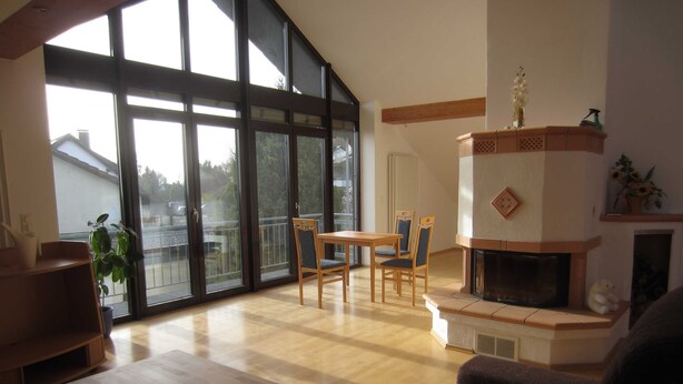 A spacious living room with a fireplace, large windows, and a balcony. - Küpfer vacation apartment (Gräfenberg)