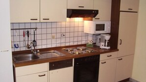 Eine kleine Küche mit Spüle, Herd, Mikrowelle und Geschirrspüler.