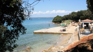 A coastal hotel with a beach area, outdoor seating, and a view of the sea. - Holiday apartment with one bedroom and balcony with sea view (Fažana)