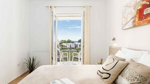 A bedroom with a bed, a view of the outside, and a window. - Holiday apartment with one bedroom and balcony with sea view (Fažana)