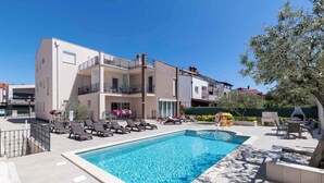 A modern building with a swimming pool, sun loungers, and outdoor seating. - Holiday apartment with one bedroom and balcony with sea view (Fažana)