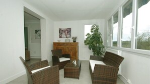 A living room with wicker furniture, a fireplace, and a large window with a view. - Stunning home in Eyliac (Eyliac)
