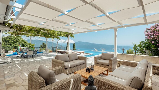 Un espacio al aire libre con mobiliario de mimbre, una piscina y vista al mar.