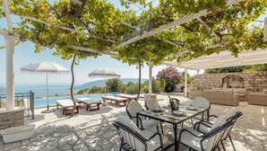 Un patio exterior con piscina, zona de comedor y asientos.