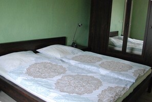 Ein Bett mit einem gemusterten Bettüberwurf, eine Nachttischlampe und ein Spiegel an der Wand.