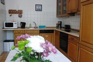 Eine Küche mit Mikrowelle, Kaffeemaschine, Spüle und Holzschränken.
