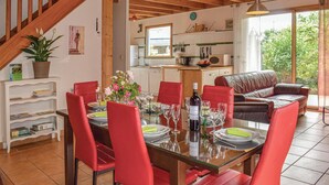 A dining area with a glass table, red chairs, and a kitchen in the background. - Nice home in Plounéour-Trez with sauna (Plounéour-Trez)