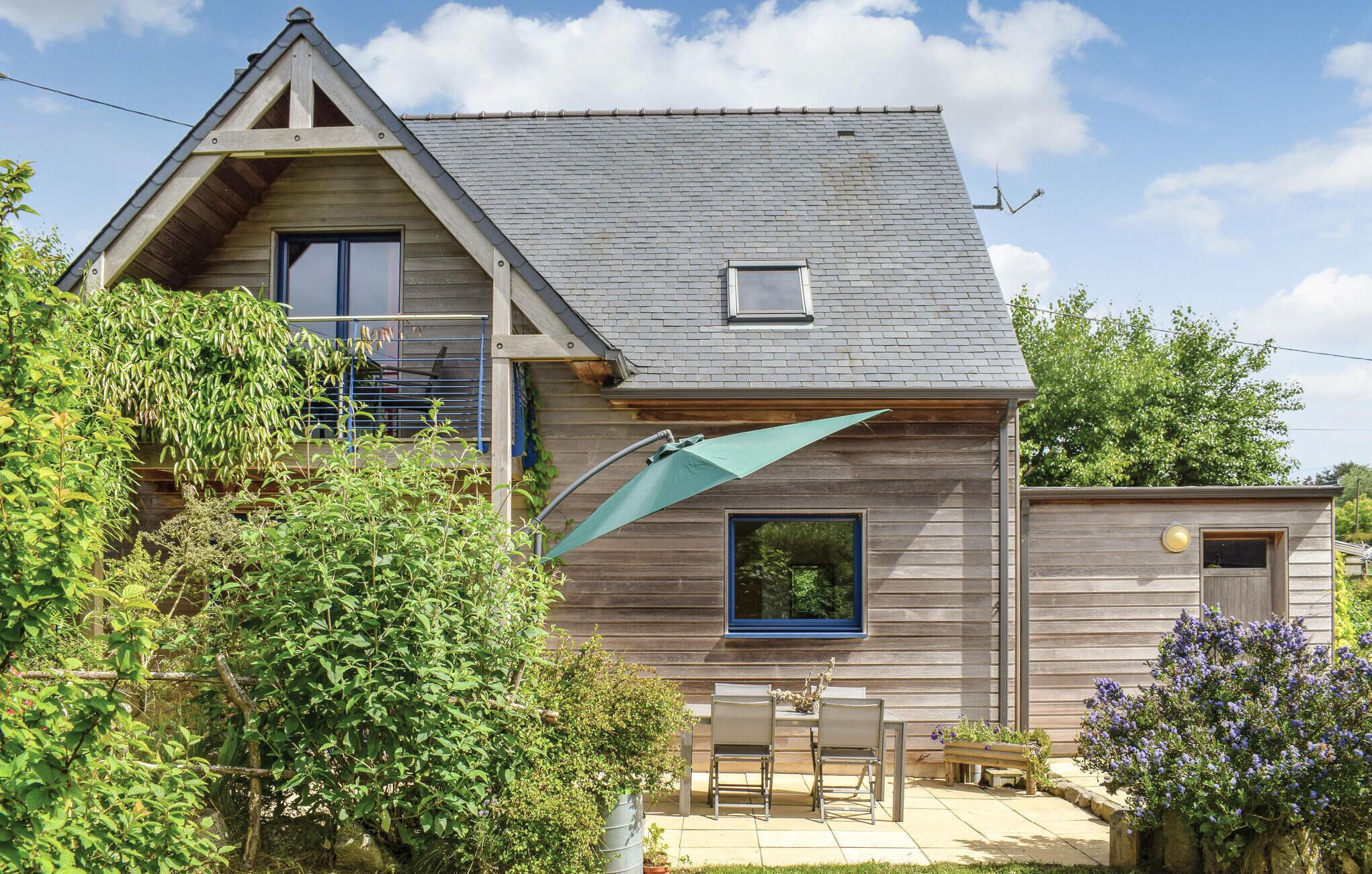 A wooden house with a sloped roof, a small window, and a patio with outdoor furniture.
