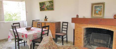 A dining area with a table set for four, a fireplace, and a painting on the wall.