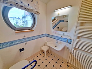 Ein Badezimmer mit Fenster, Waschbecken, Toilette und Spiegel.