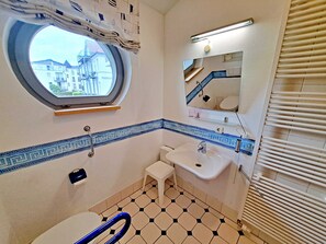A bathroom with a window, a sink, a toilet, and a mirror.