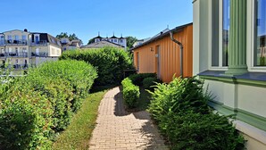 Un camino que lleva a una hilera de edificios residenciales con un seto verde a un lado.