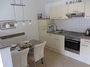 Cozinha moderna com armários brancos, forno de aço inoxidável e painel de azulejos.