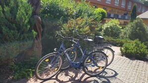 En cykel parkerad på en asfalterad yta, med en byggnad i bakgrunden.