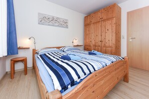 Une chambre à coucher avec un lit en bois, deux tables de chevet, une armoire et une œuvre d’art accrochée au mur.