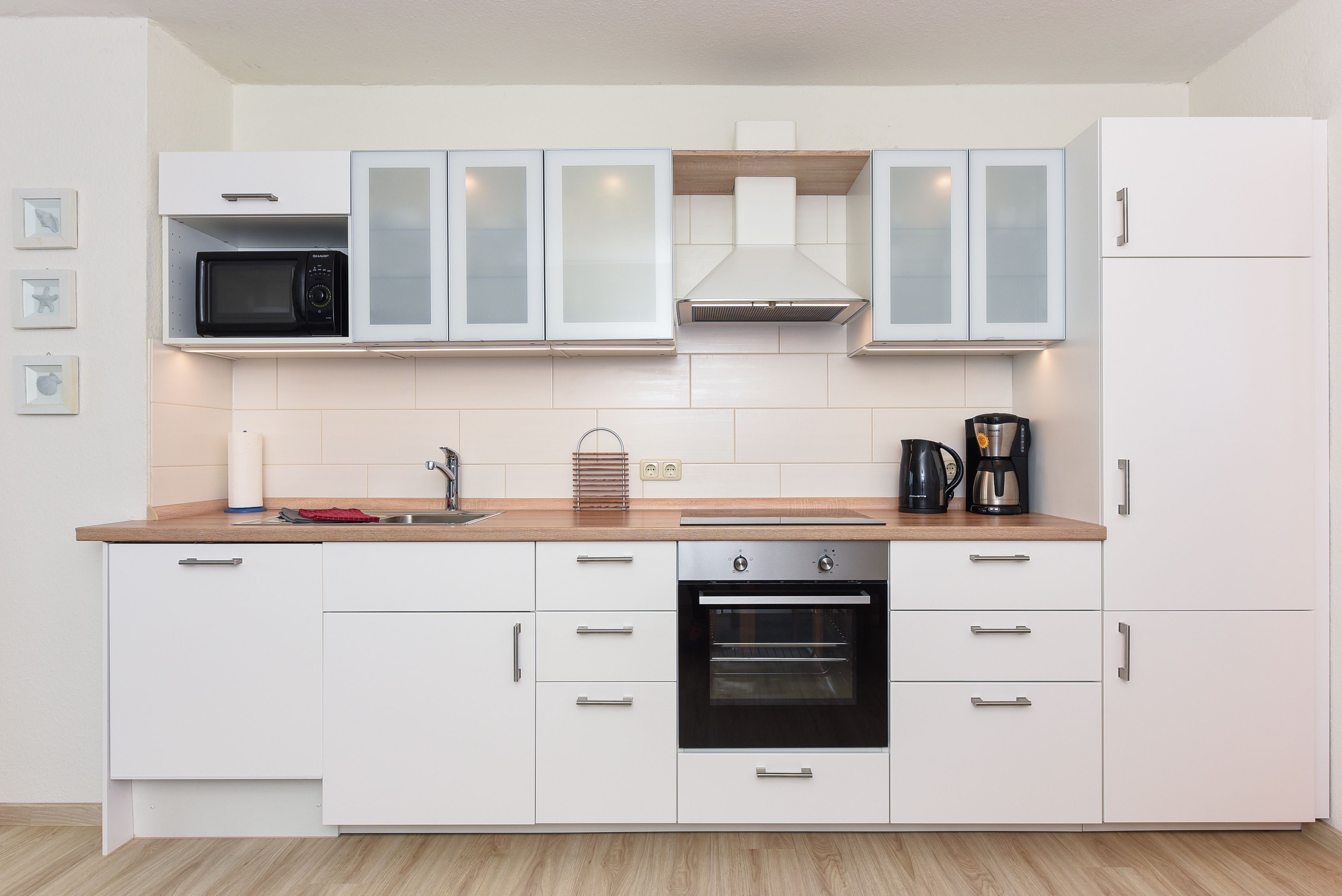 Una cucina moderna con mobili bianchi, un forno a microonde, un forno e una macchina per il caffè.