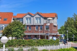 A multi-story building with a red-tiled roof, a balcony, and a sign indicating a business establishment.