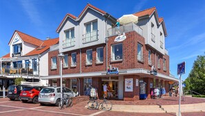 En tvåvåningsbyggnad med en butikslokal i bottenvåningen, en cykel parkerad utanför och en klarblå himmel.