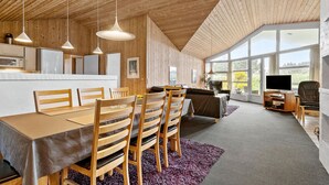 A modern kitchen with wooden cabinetry and a dining area with a large table and chairs. - Amazing home in Blåvand with sauna (Blåvand)