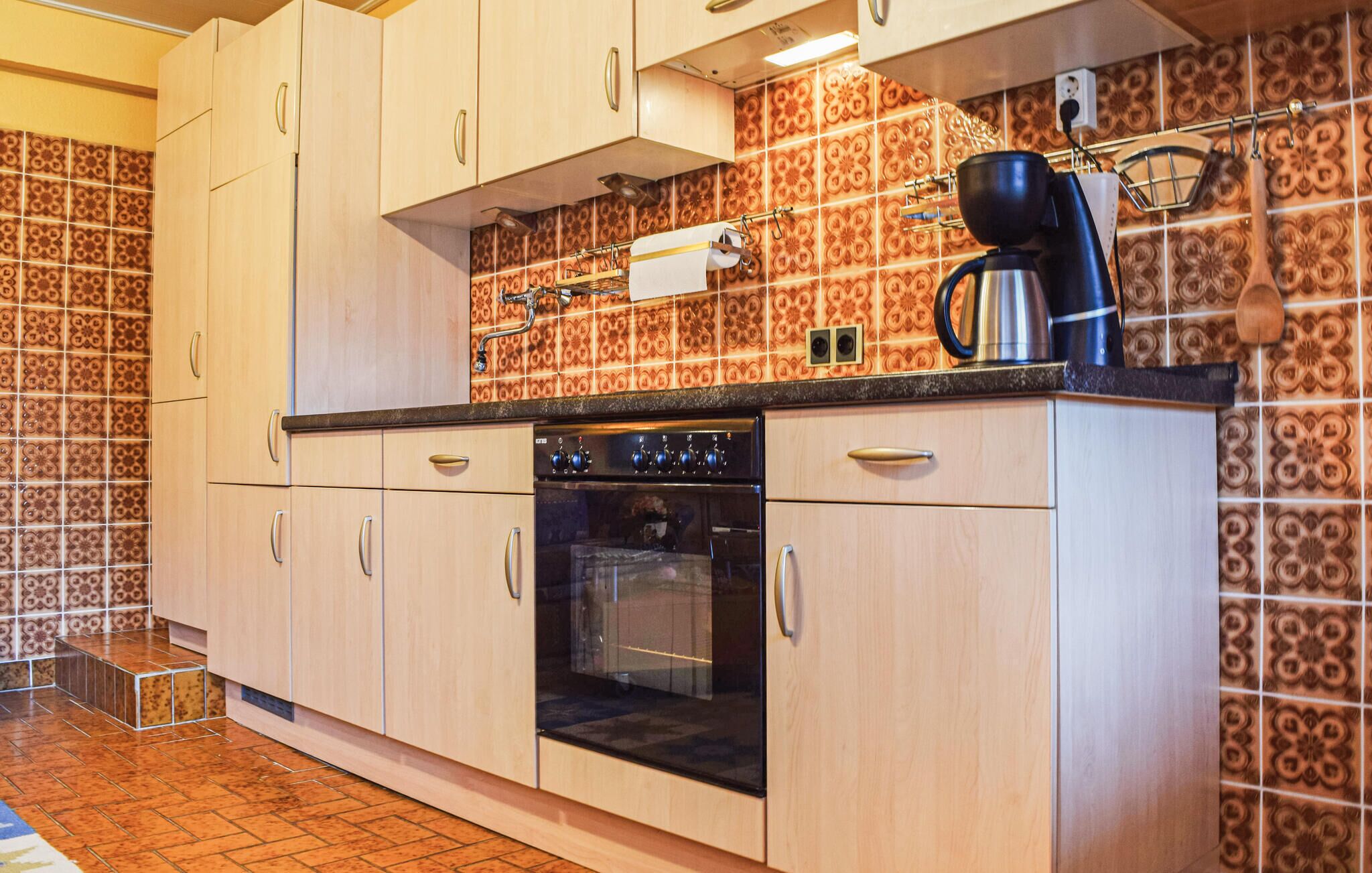 A kitchen with wooden cabinets, a black oven, and a coffee maker on the countertop.