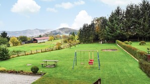 A well-maintained grassy yard with a swing set, picnic table, and a fenced area. - Beautiful apartment in Reifferscheid (Reifferscheid)